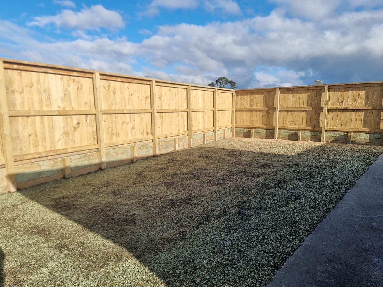 A finished timber fence on a Tensen Landscapes job in Hamilton, with a low retaining board and drainage bed behind it