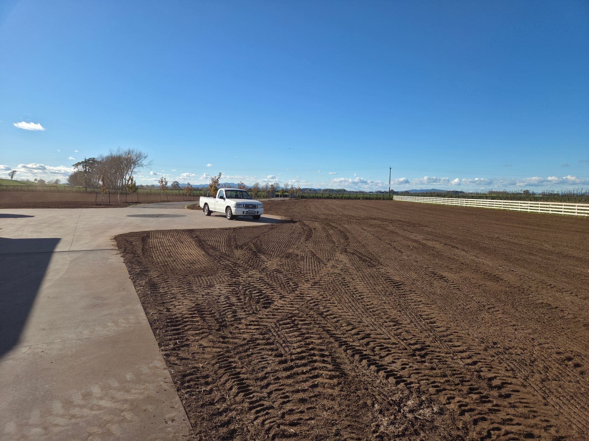 A tractor towing a dimple seeder across a cultivated lifestyle block section in Gordonton