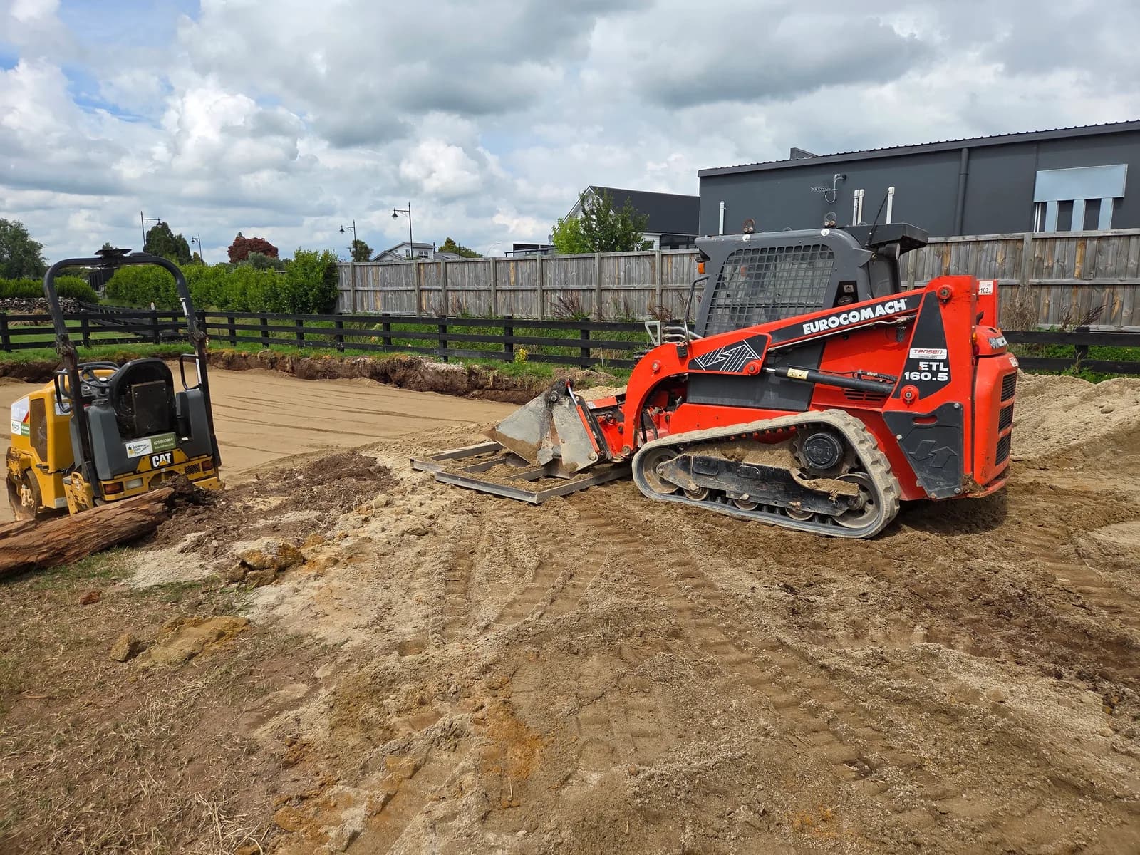 A Tensen Landscapes skid steer and mini loader clearing and levelling a section along the fenceline before the next job starts