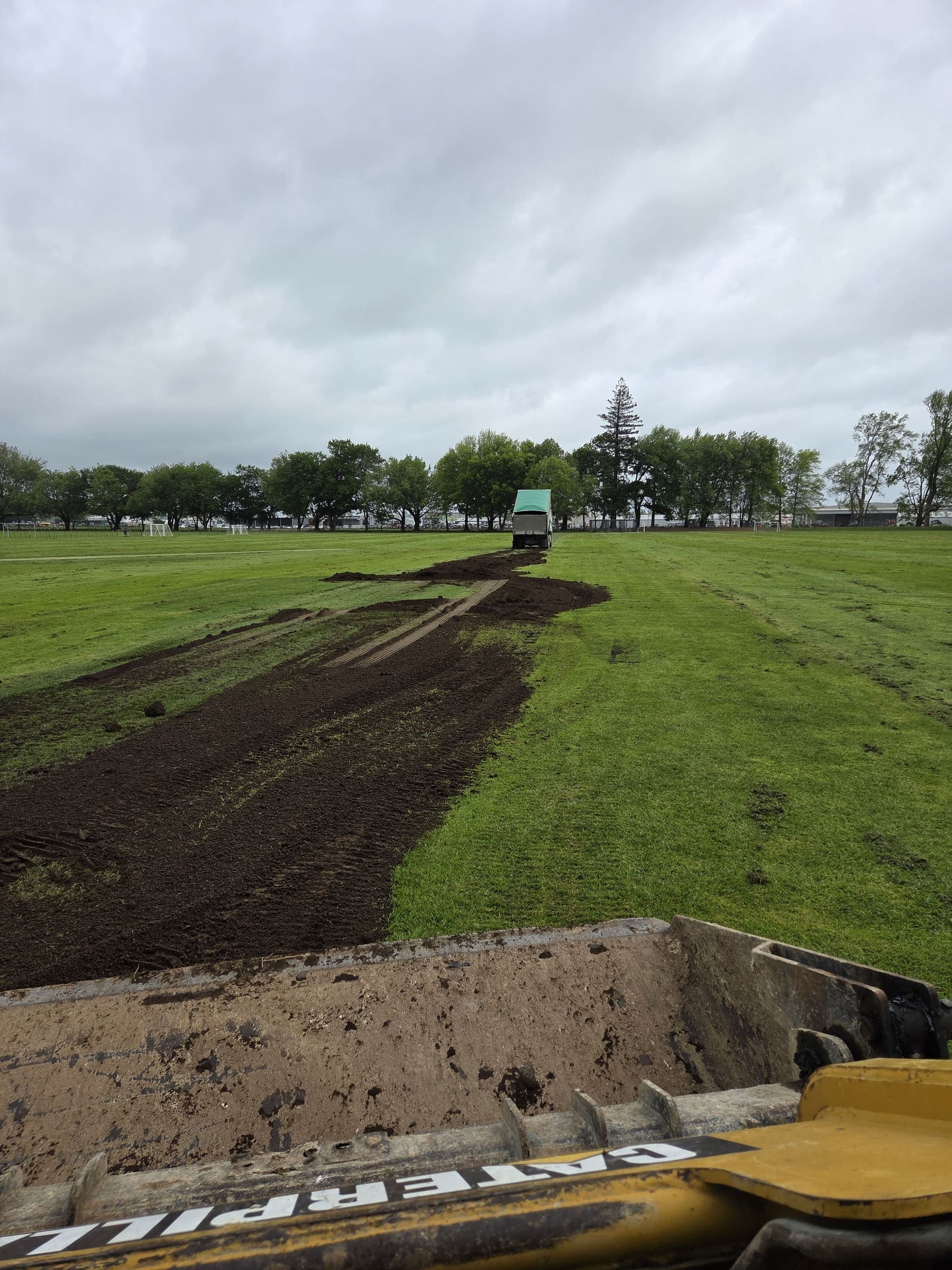 Bobcat trenching and topsoil work across a sports field