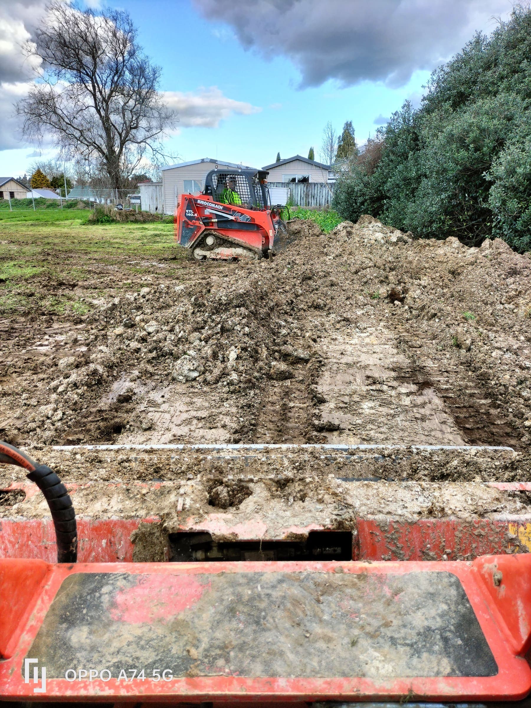 Skid steer clearing topsoil on a residential section